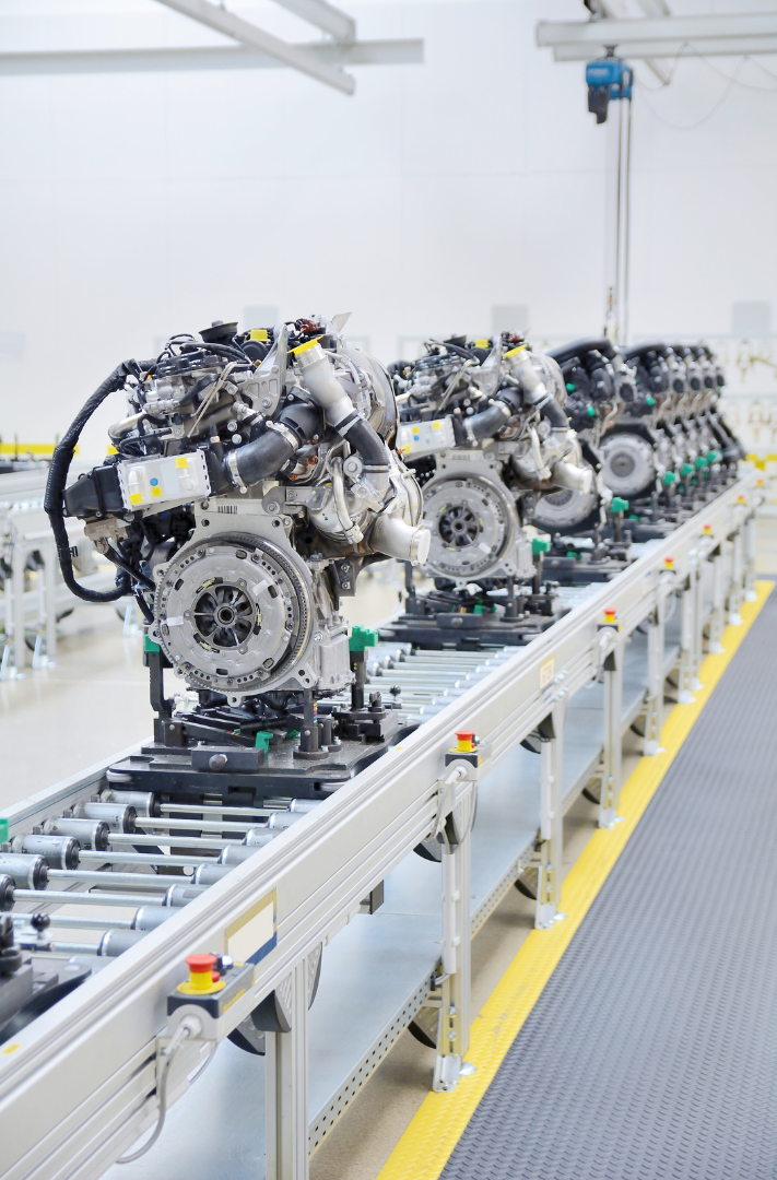 Automotive engines positioned on a conveyor system in a manufacturing facility.